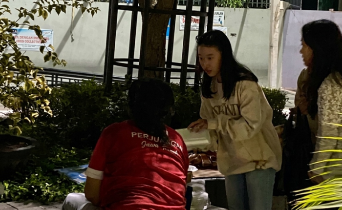 A GERSOS participant handing a food package to a community member.