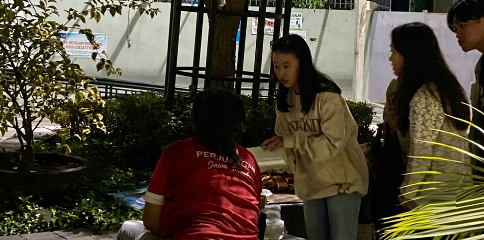 A GERSOS participant handing a food package to a community member.