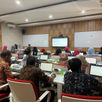 Suasana pelatihan di dalam ruang kelas modern di mana puluhan peserta sedang duduk menghadap laptop masing-masing sambil memperhatikan layar presentasi di depan kelas.