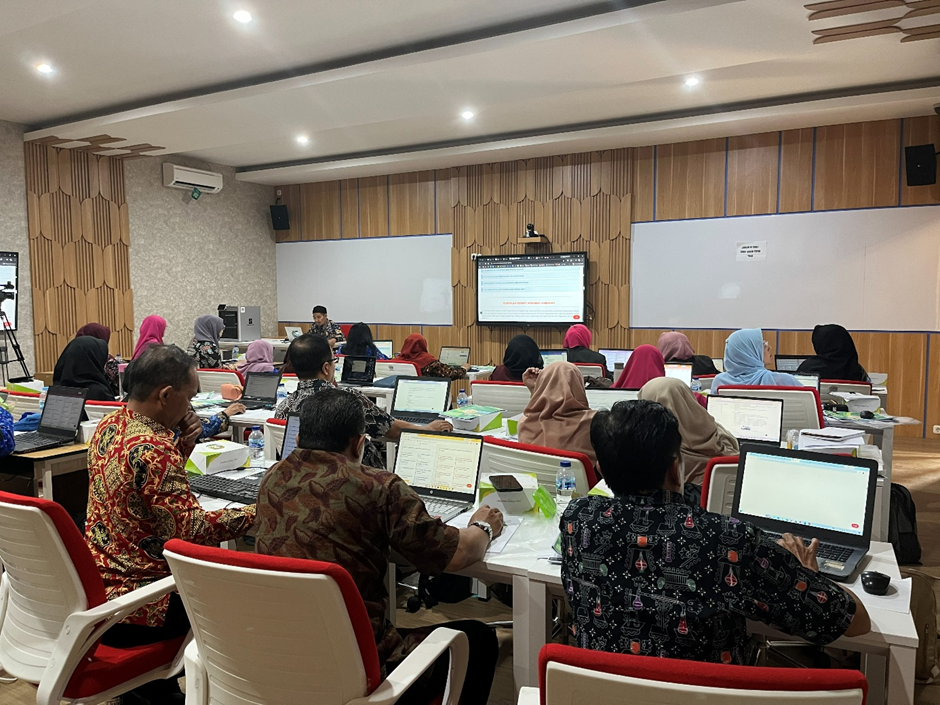 Suasana pelatihan di dalam ruang kelas modern di mana puluhan peserta sedang duduk menghadap laptop masing-masing sambil memperhatikan layar presentasi di depan kelas.