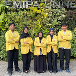 Five students consisting of two males and three females wearing yellow alma mater jackets, posing with folded arms against a green vertical garden background with the text FMIPA UNNES.