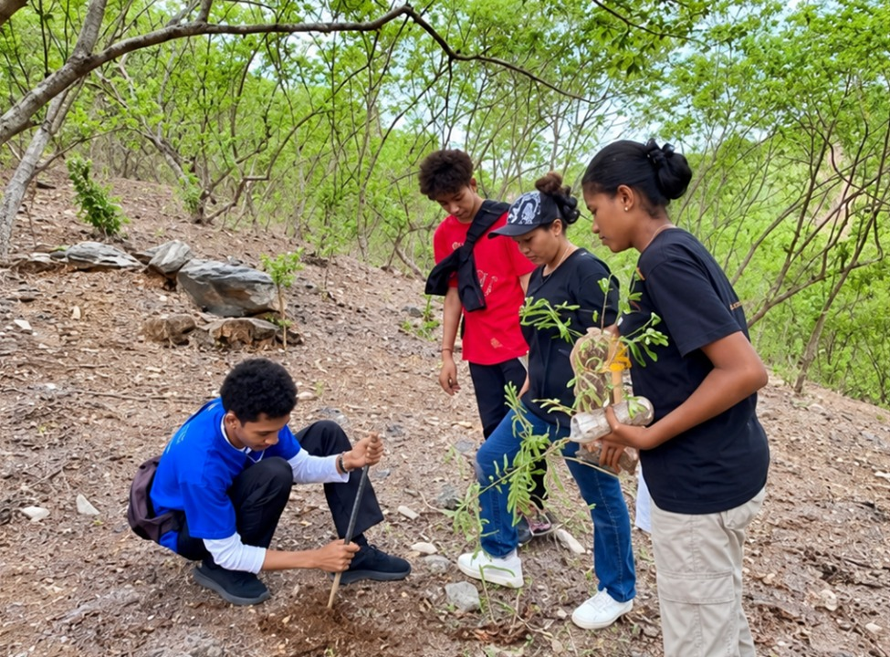 Empat orang pemuda berada di area perbukitan berpasir dan berbatu yang kering. Seorang pemuda berbaju biru sedang berjongkok menggali tanah menggunakan tongkat, sementara tiga pemuda lainnya berdiri memperhatikannya, dengan salah satu perempuan memegang bibit pohon yang siap ditanam.