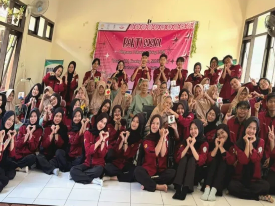 Dozens of Himabio FMIPA UNNES student board members wearing maroon organizational shirts posing with hand hearts alongside elderly residents in front of a banner reading Biology Student Association Social Service.